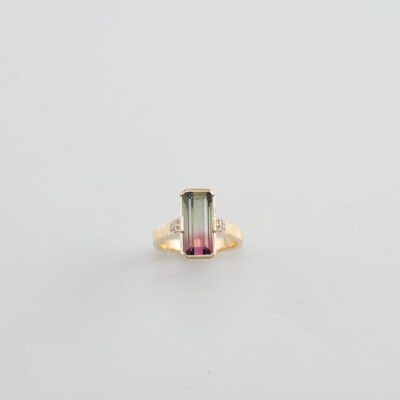 This bi-color tourmaline ring has white diamond accents. Both the diamonds and the tourmaline have been set in 14kt yellow gold.
