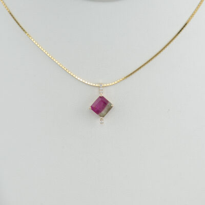 This bi-color tourmaline pendant is one of a kind. The bi-color tourmaline has a squared cut and is accented with white diamonds. Both the diamonds and the bi-color tourmaline have been set in 14kt yellow gold. We also have earrings to match.