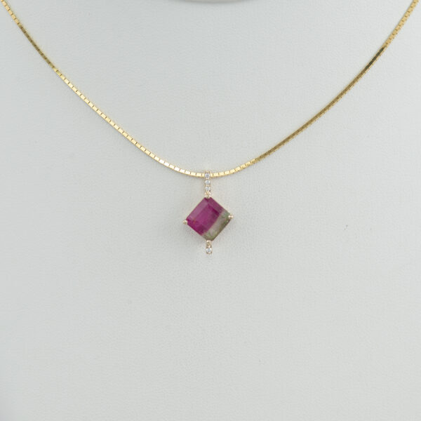 This bi-color tourmaline pendant is one of a kind. The bi-color tourmaline has a squared cut and is accented with white diamonds. Both the diamonds and the bi-color tourmaline have been set in 14kt yellow gold. We also have earrings to match.