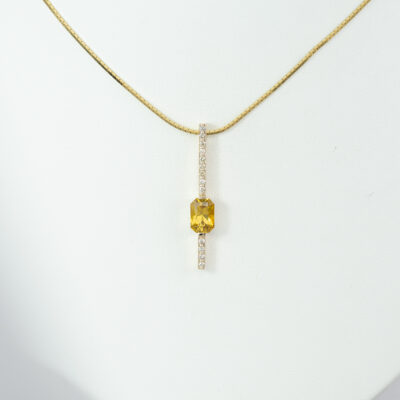 This pendant has a radiant cut yellow sapphire. Accenting the golden yellow sapphire are round, brilliant cut diamonds. Chain not included.