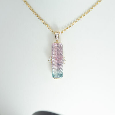 This bi color tourmaline pendant has been given a zig-zag fantasy cut. Accenting the tourmaline are white diamonds. Chain not included.