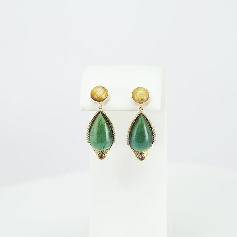 These rutile quartz earrings have green tourmaline cabochons. Accenting the green tourmaline are white and cognac diamonds. We also have a pendant to match.
